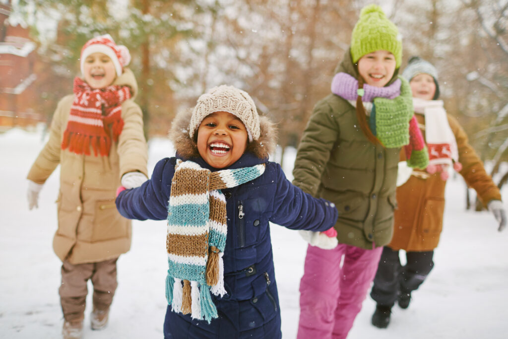 Happy girl holding her friends by hands in snowfall