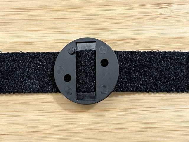 Round plastic Specs strap base with strip of black velcro threaded through it. 