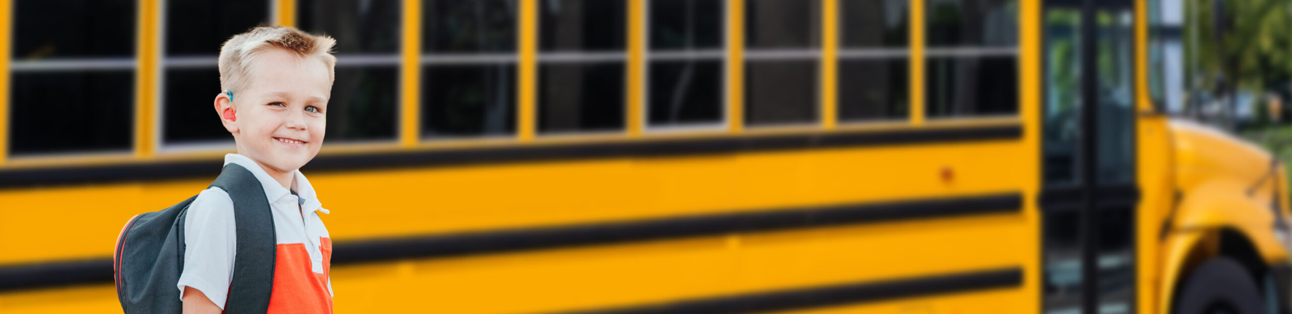 boy standing next to a school bus