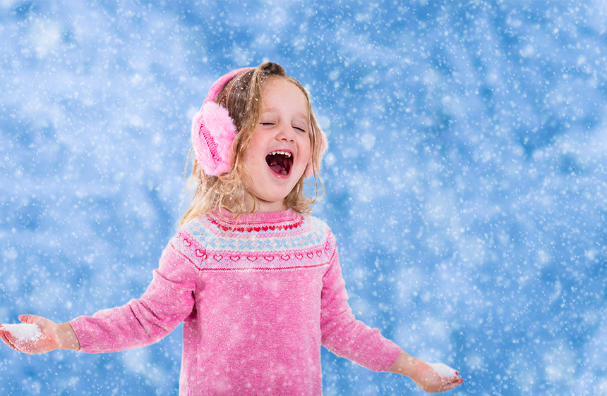 Young girl in pink enjoying a light dusting of snow outside