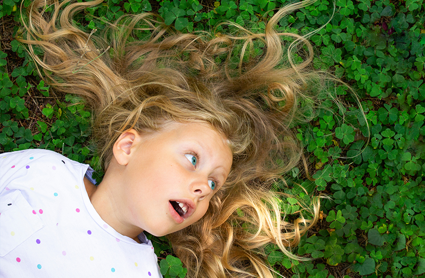 Girl laying down in a bed of clovers