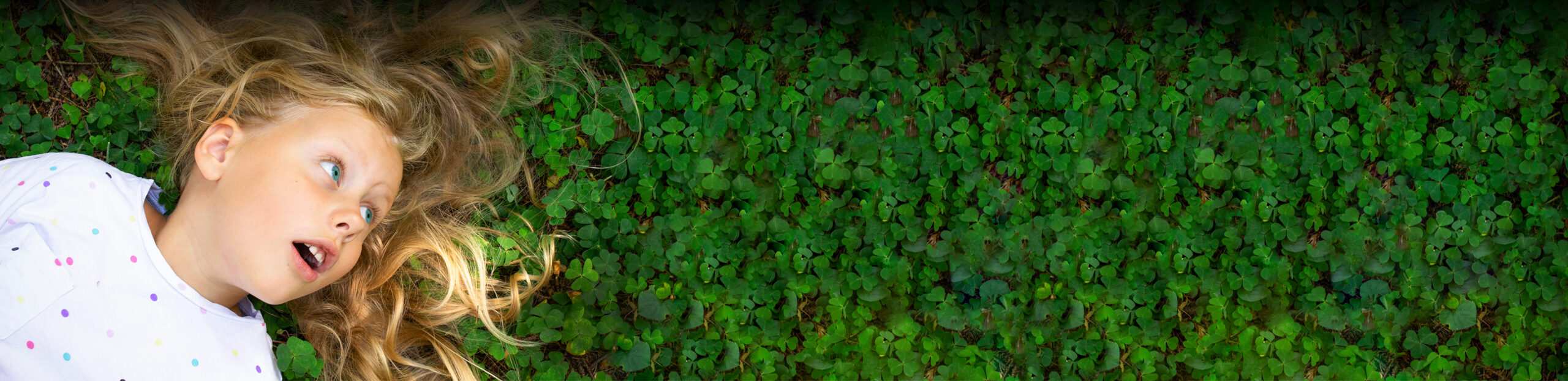 Girl laying down in a bed of clovers